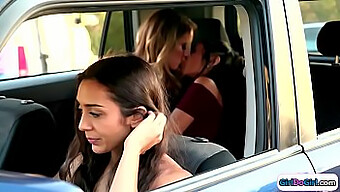 Lilly Hall and Candice Dare engage in passionate kissing in the rear seat of a car, observed by the driver